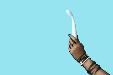 Female hand in black laced glove with vibrator on color background