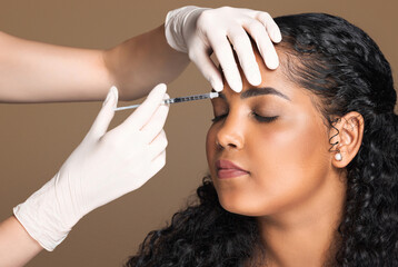 Cosmetologist making botox injection in interbrow zone to latin chubby woman getting anti-wrinke...