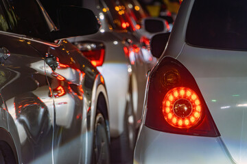 Taillight of a white car waiting in line at night city.