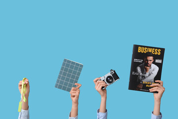 Journalist's female hands with magazine, camera and badge on blue background