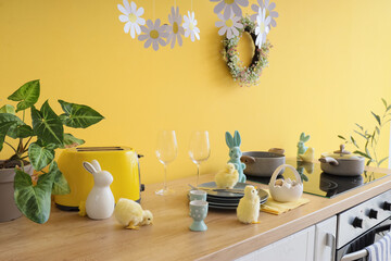 Interior of festive kitchen with oven, utensils and Easter decorations on counter near yellow wall