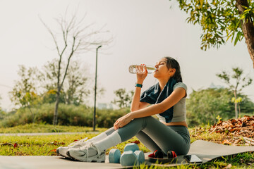 A woman dressed in workout clothes is drinking water during a break from exercising. Sport, Exercise, Workout, Yoga and fitness concept.