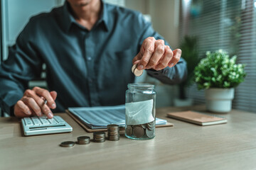 Businessman putting coins saving money with jar coin on desk. income, deposit, financial planning and investment concept.
