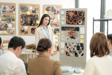 Obraz premium Young Asian professionals collaborate in a sustainable packaging design studio, examining eco-friendly containers and recycled materials for innovative product solutions.