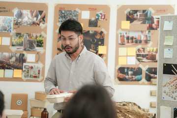 Obraz premium Asian designer presents eco friendly food containers to team members