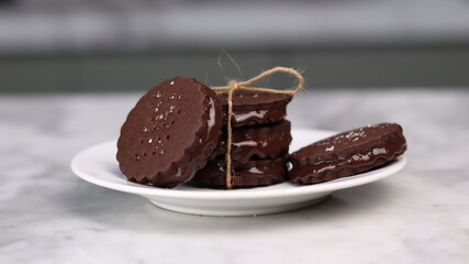 chocolate cookies arranged on a white plate with a marble table background