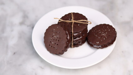 chocolate cookies arranged on a white plate with a marble table background