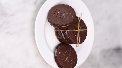 chocolate cookies arranged on a white plate with a marble table background