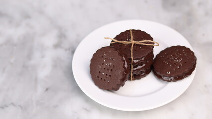 chocolate cookies arranged on a white plate with a marble table background