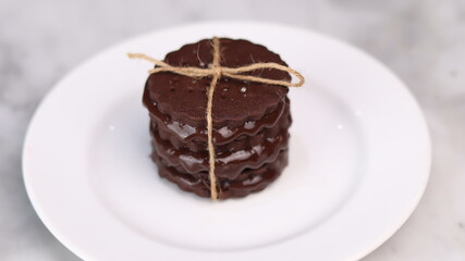 chocolate cookies arranged on a white plate with a marble table background