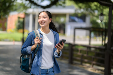 Happy student walking on campus using smartphone, enjoying university life and modern technology