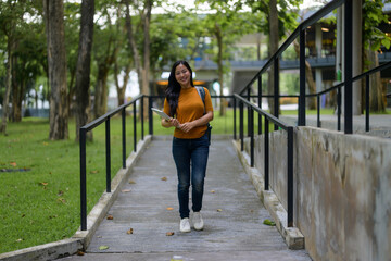 Portrait of young beautiful Asian woman student walking outdoors on campus