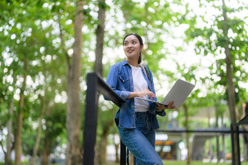 Asian student working with laptop outdoor in university campus park