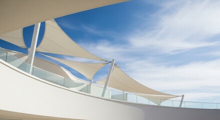 A modern architectural structure featuring white tensile fabric canopies providing shade against a bright blue sky with wispy clouds.