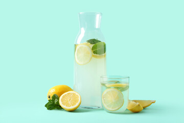Glass and bottle of fresh lemonade with mint on turquoise background