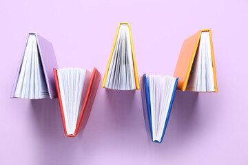 Open colorful books on lilac background