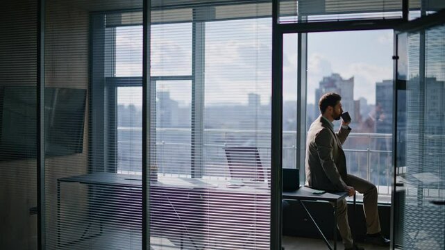 Wealthy businessman enjoying coffee pause sitting office watching large window