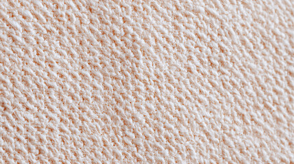Close up detailed texture of soft beige knitted fabric showing warm cozy pattern and natural fiber threads for textile and fashion background