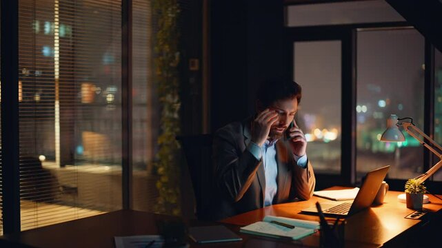 Nervous boss talking mobile phone at dark office. Lawyer tensed conversation