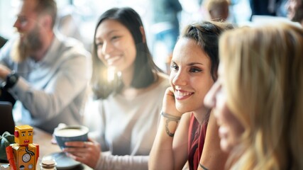 People enjoying coffee at a cafe. Happy diverse friends socializing. Bright atmosphere, casual setting, friendly interaction. Diverse friends talking at the coffee shop. Diverse women enjoy at cafe
