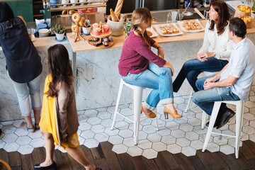 Casual cafe with people socialize, enjoying pastries. Casual setting, diverse group. Relaxed cafe...