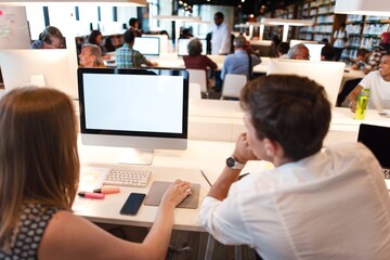 Modern library with diverse people working on computers. Open space with collaborative work environment. Bright library with tech focus. Teen students learning on computers in school library.