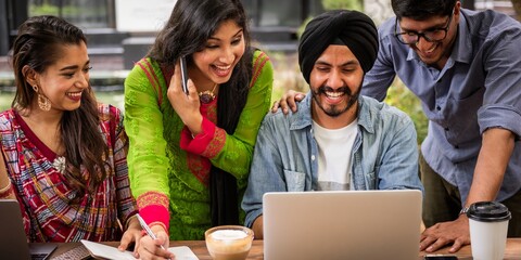 Group of diverse people collaborating, smiling, and working on laptops. Teamwork and collaboration in a friendly, diverse setting. Happy group at work. Indian students working together on laptop.