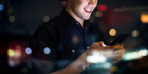 Man smiling using smartphone night