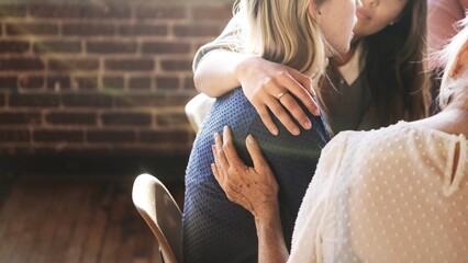 A comforting scene with three women sharing support. One woman embraces another, showing care and...