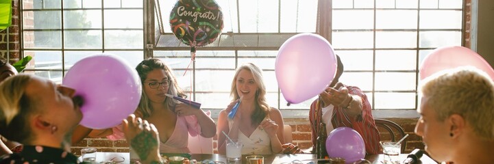 Obraz premium Group celebrating with balloons and party hats. Diverse friends enjoying festive gathering. Bright, cheerful atmosphere with decorations and laughter. Diverse friends celebrate festive birthday party.