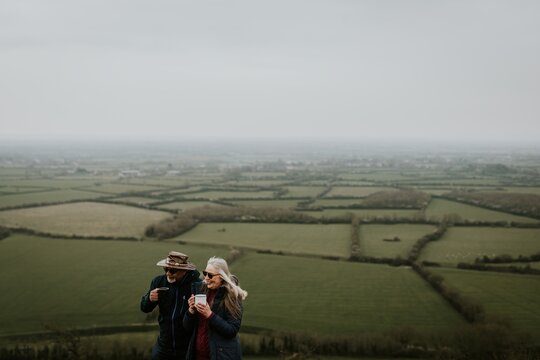 Elderly couple enjoying a scenic view. The couple, a man and woman, admire the landscape. The elderly pair stands together, embracing the view. Senior couple on a hike in the countryside.
