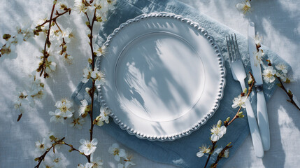 Fototapeta premium Elegant spring table setting engulfed in soft natural light, featuring cherry blossom branches and a classic white plate with blue trim 