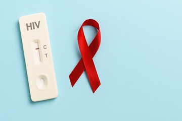 HIV Test Kit with Positive Result Next to Red Awareness Ribbon on Light Blue Background for Health and Medical Awareness Initiatives