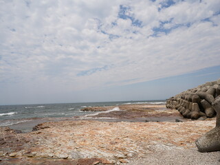 Rocky Japanese Coastline with Breakwaters and Blue Sky