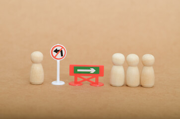 Wooden peg dolls divided by traffic signs symbolizing no left turn and mandatory right turn on,...