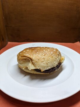 Mini burger on a white plate, with a wood and orange background