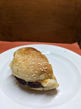 Mini burger on a white plate, with a wood and orange background