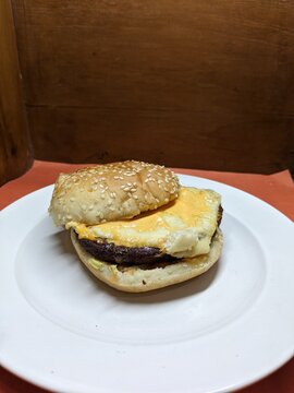 Mini burger on a white plate, with a wood and orange background