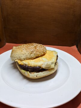 Mini burger on a white plate, with a wood and orange background