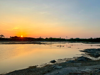 Sunset Over the Peaceful Waters of Talay Prong Lake in Nakhon Si Thammarat, Thailand, with Warm Light Reflecting on the Serene Landscape