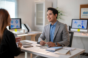 A man and a woman are sitting at a desk in a business setting