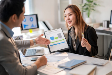 A man and a woman are sitting at a desk with a presentation in front of them
