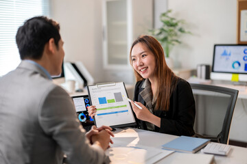 A man and a woman are sitting at a desk with a presentation in front of them
