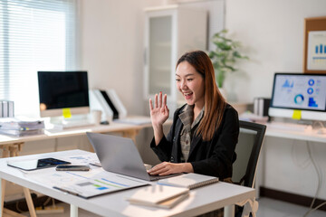 A woman is sitting at a desk with a laptop and smiling