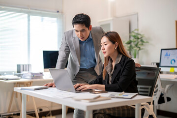 A man and a woman are working together at a desk