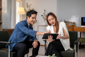 Fototapeta premium A man and a woman are sitting in chairs and looking at a tablet