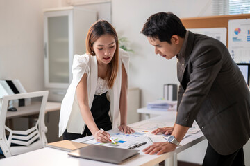 A man and a woman are sitting at a desk looking at a piece of paper