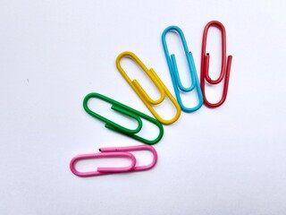 Multicolored paper clip arranged on white background.