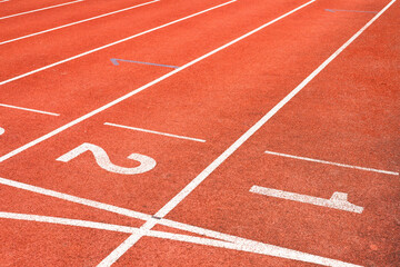 Red running track with numbered starting lines outdoor for organizing sports competitions and exercising for health.