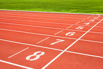 Red running track with numbered starting lines outdoor for organizing sports competitions and exercising for health.